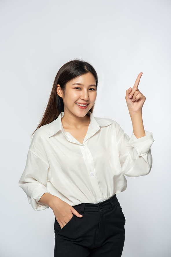 a young woman in a white shirt and pointing up.